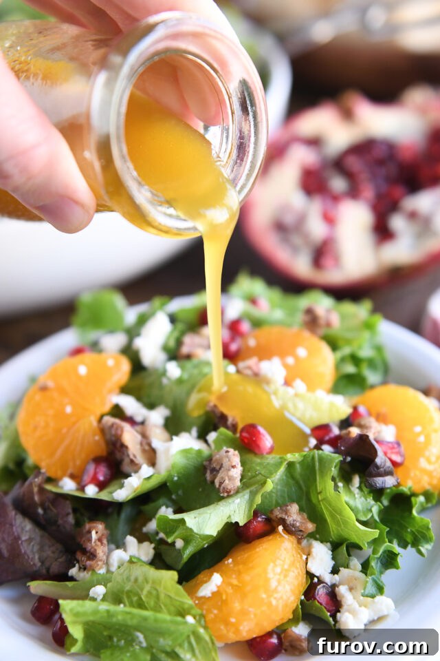 A hand gently pouring a light vinaigrette dressing over a bed of fresh salad greens on a white plate, preparing it for serving.