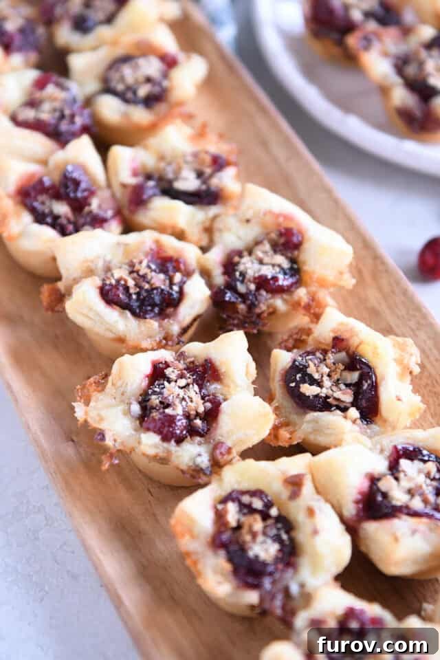 Sweet & Savory Brie Cranberry Puffs 2 Lots of baked cranberry brie bites on wood platter.