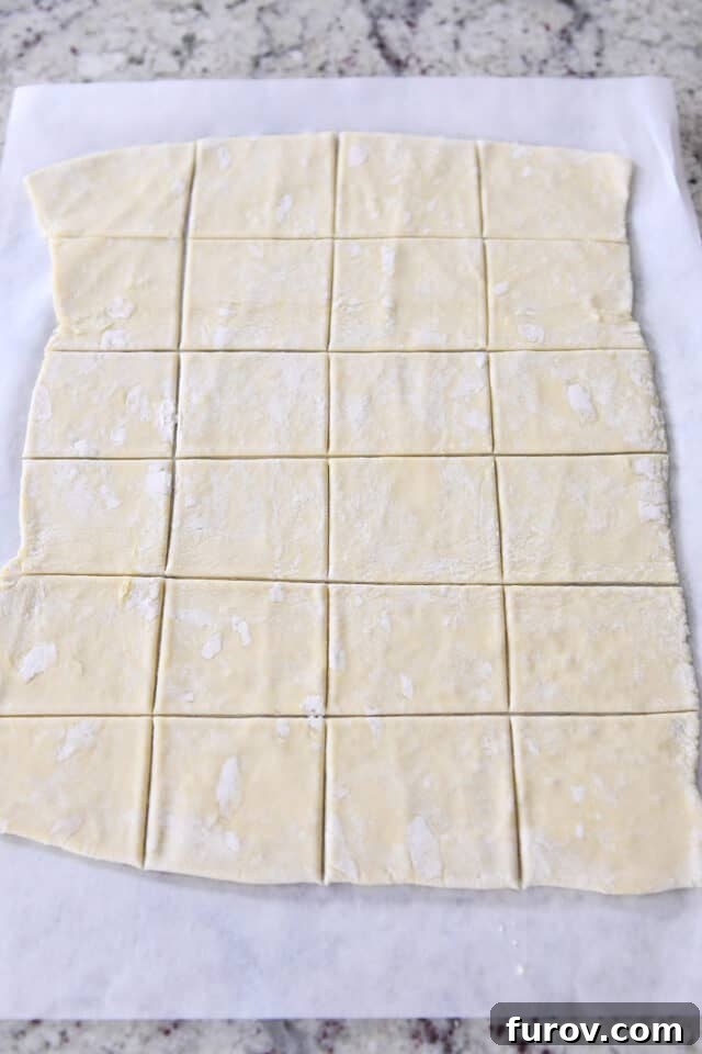 Sweet & Savory Brie Cranberry Puffs 3 Rolled sheet of puff pastry on parchment paper cut into squares.