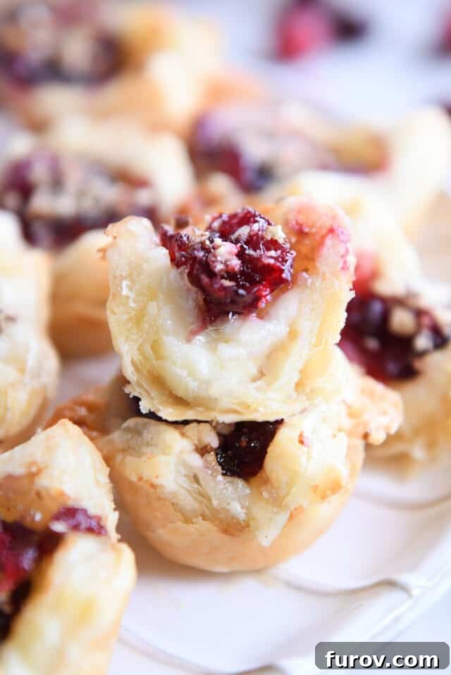 Sweet & Savory Brie Cranberry Puffs 9 Cranberry brie bite bit in half stacked on top of another puff pastry bite.