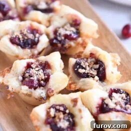 Six cranberry brie bites on wood platter.