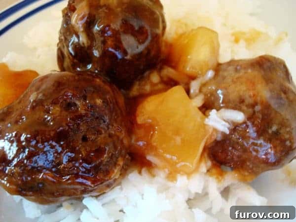 Delicious pineapple meatballs on a bed of fluffy white rice, garnished with fresh herbs.