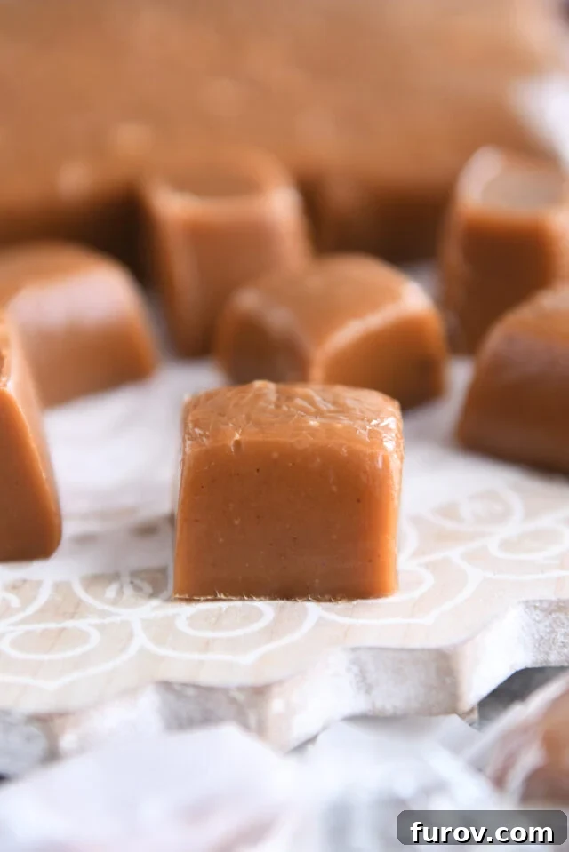 One perfectly square gingerbread caramel resting on a decorated wooden board, showcasing its clean edges and inviting color.