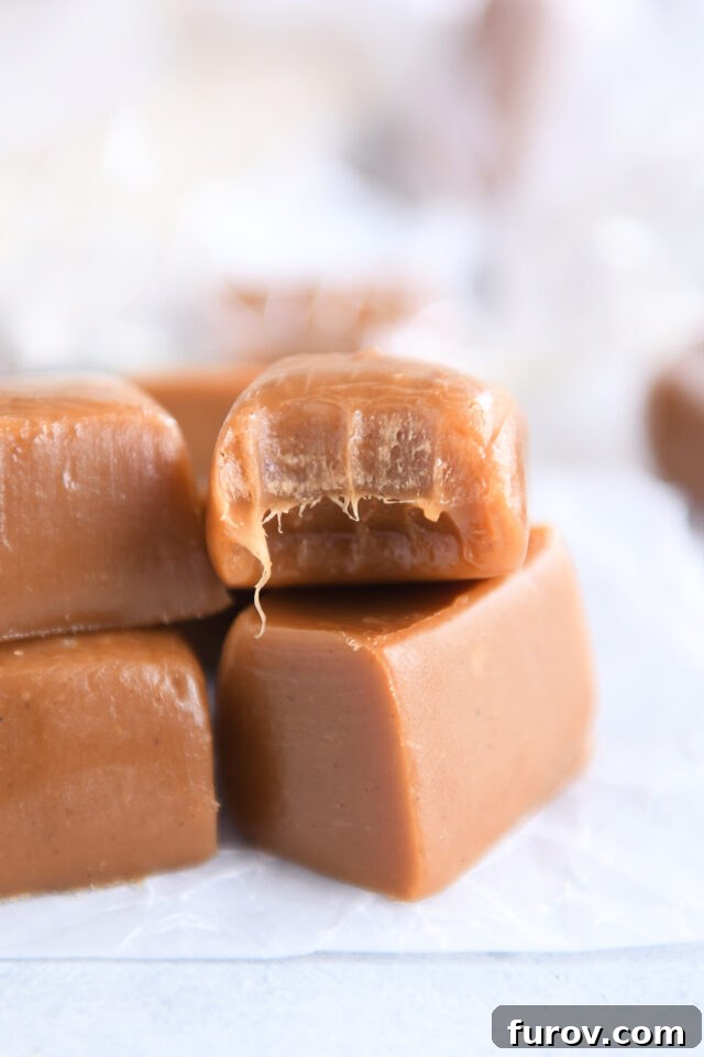 Several gingerbread caramels arranged on white parchment paper, with one caramel having a bite taken out, revealing its soft interior.