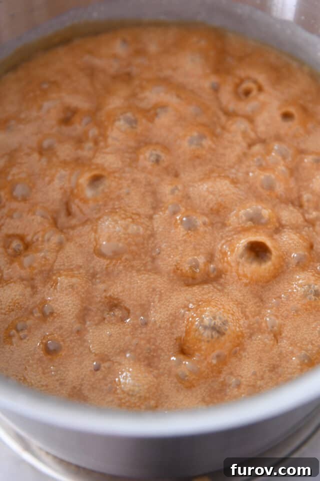 Bubbling golden caramel in a saucepan during the early stages of cooking, showing a frothy texture.