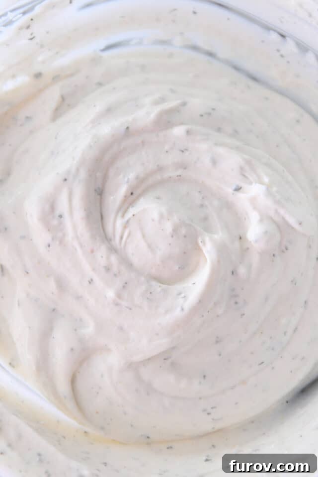 A glistening glass bowl showcasing the perfectly creamy and smooth texture of the freshly prepared veggie dip, ready to be enjoyed.