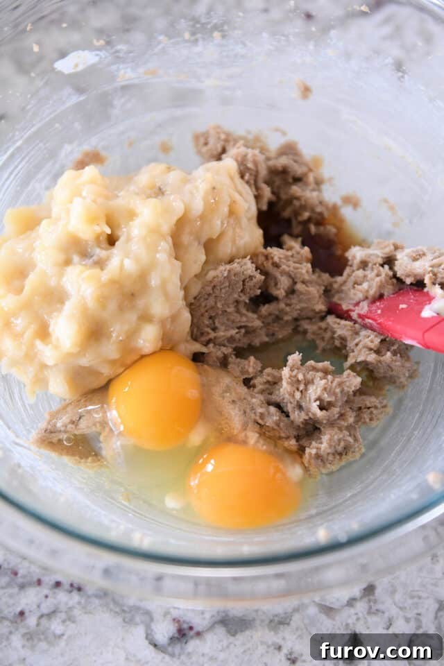 Glass bowl with mashed bananas, eggs, brown sugar and butter.