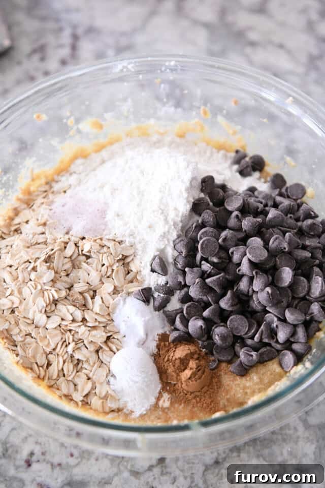 Glass bowl with oats, flour, chocolate chips, cinnamon, salt, banana batter.