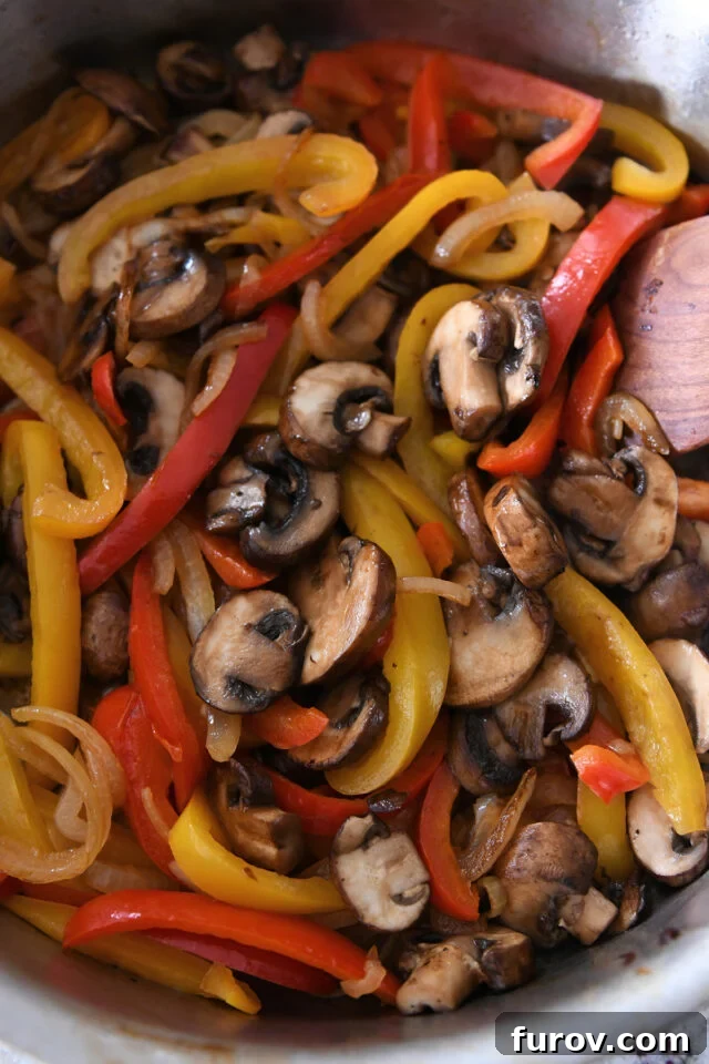 Zesty Chicken Fajita Sweet Potato Bowls 3 Pan filled with vibrant bell peppers, onions, and mushrooms sautéing to perfection.