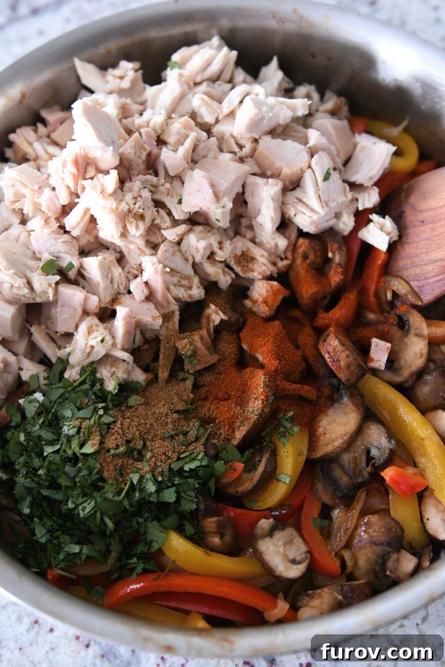 Zesty Chicken Fajita Sweet Potato Bowls 4 Pan filled with sauteed bell peppers, mushrooms, cilantro, cumin, chili powder, and cooked chicken, all mixed together.