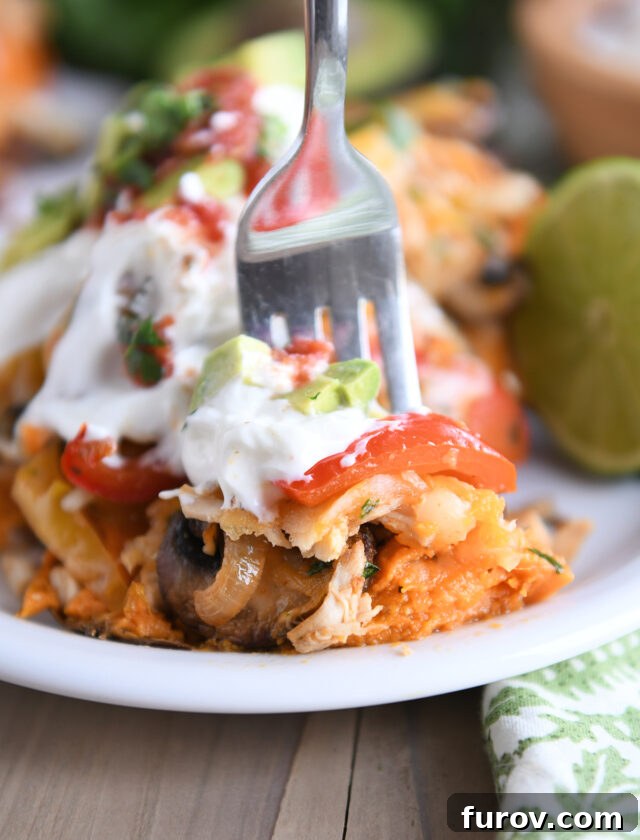 Zesty Chicken Fajita Sweet Potato Bowls 7 Fork taking a bite of sweet potato loaded with bell peppers, mushrooms, sour cream, and avocados.