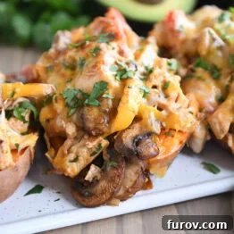 Several sweet potatoes on a white tray with mushrooms, bell peppers, and cheese, ready to serve.