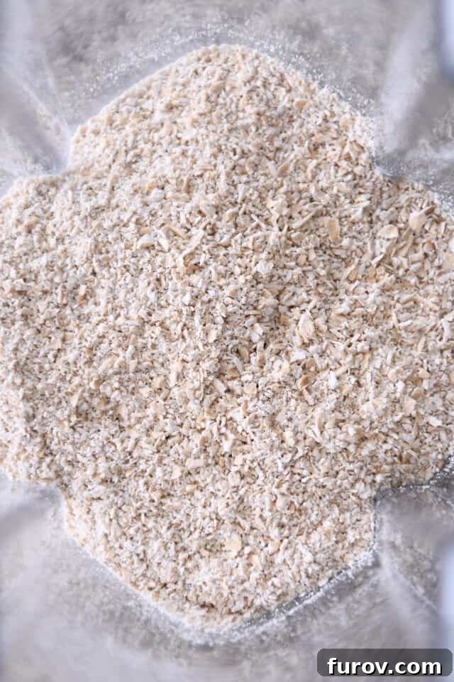 Coarsely ground oats in a blender, ready to be combined with other dry ingredients for baking vegan cookies.