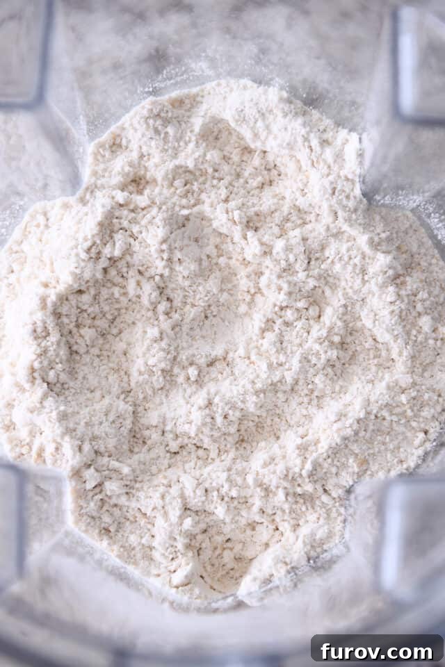 A blend of flour, coarsely ground oats, baking soda, and salt in a blender, demonstrating the combined dry ingredients for the cookie dough.