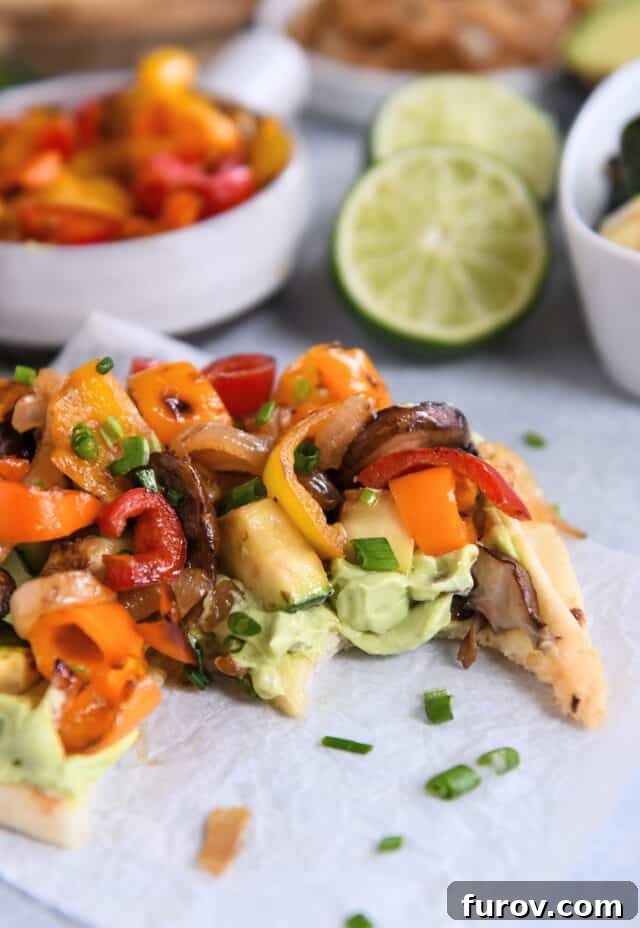 Creamy Avocado & Roasted Garden Flatbread 8 Bite taken out of flatbread with creamy avocado sauce and roasted vegetables.