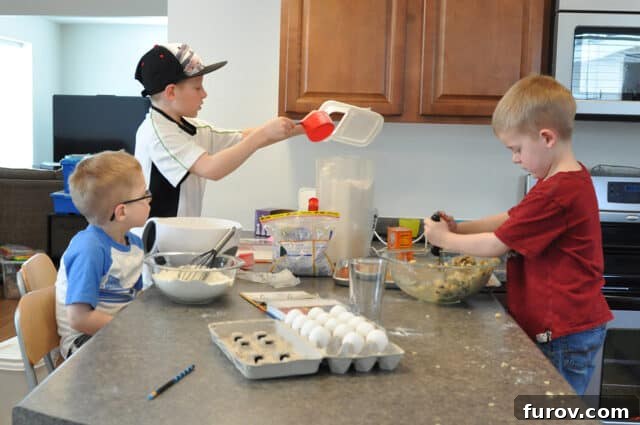 Young boys making cookies in messy kitchen.