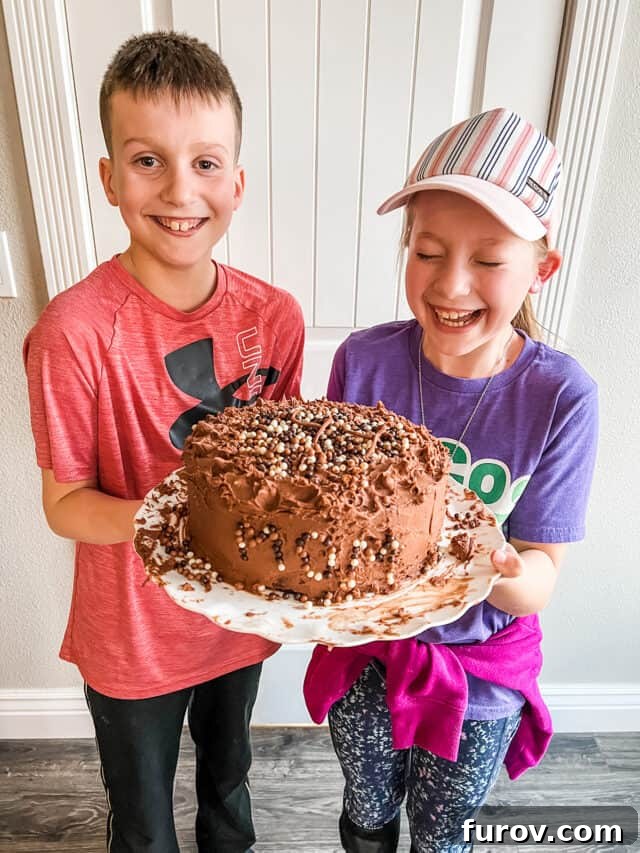 Two kids laughing and holding chocolate cake.