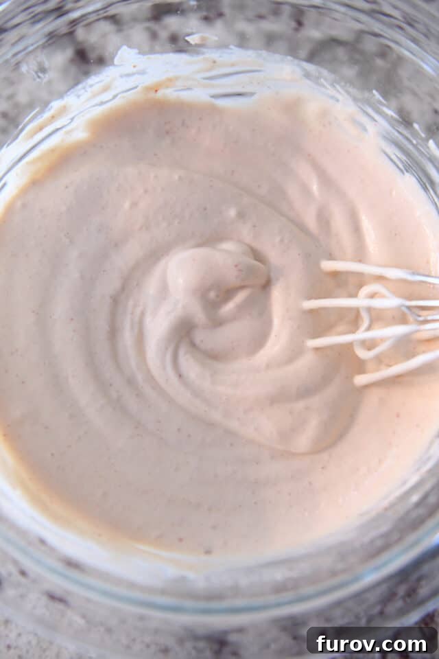 A vibrant glass bowl holds a generous portion of creamy spicy sauce, perfectly prepared and ready to be drizzled over your favorite tacos or as a zesty accompaniment to any meal.