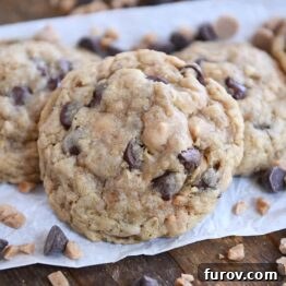 Signature Oatmeal Chocolate Chip Peanut Butter Toffee Cookies 9 One large oatmeal chocolate chip cookie with peanut butter and toffee bits on white parchment paper.