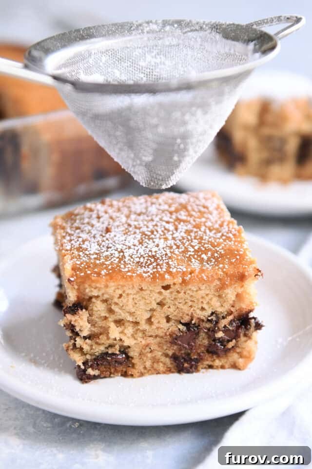 No-Fuss Chocolate Chip Cake 2 Dusting top of square piece of cake with powdered sugar.