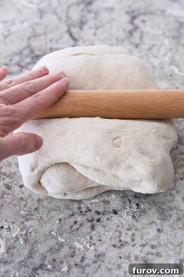 Rolling out tri-folded dough with rolling pin.