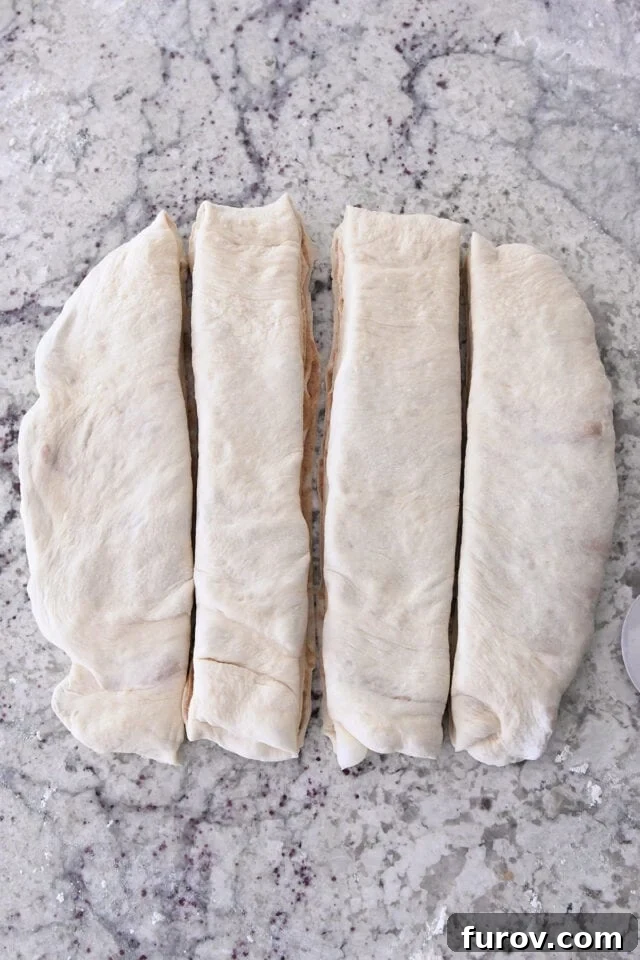 Square of dough cut into four strips for croissant bread with cinnamon sugar filling.