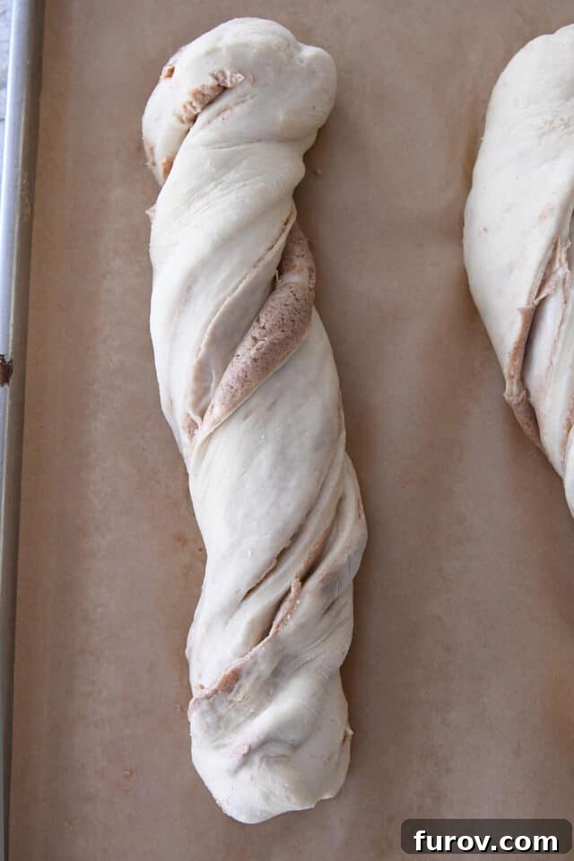 Unbaked loaf of croissant bread on brown parchment paper.