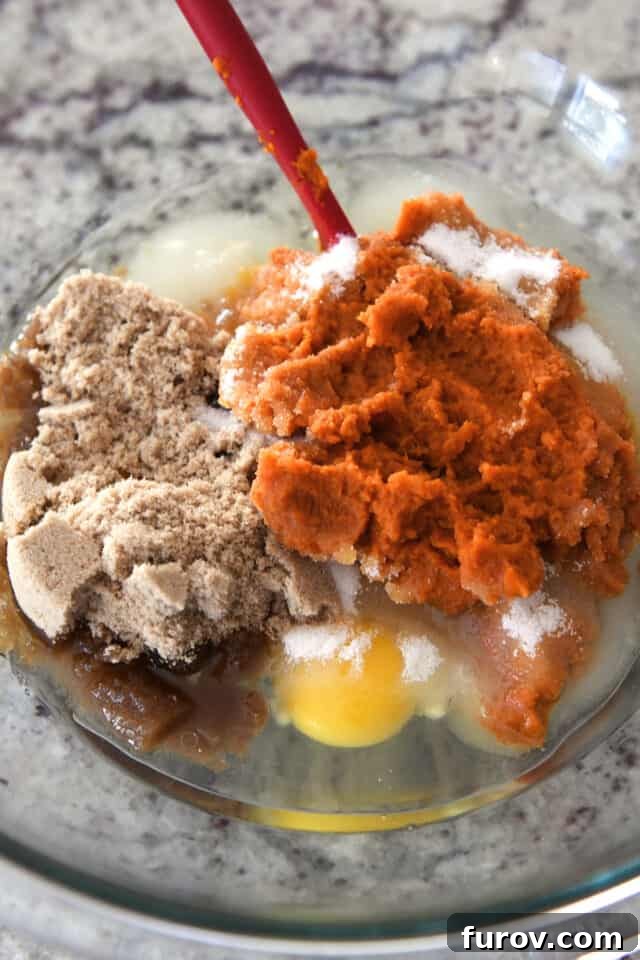 Brown sugar, eggs, pumpkin puree and sugar in glass bowl.