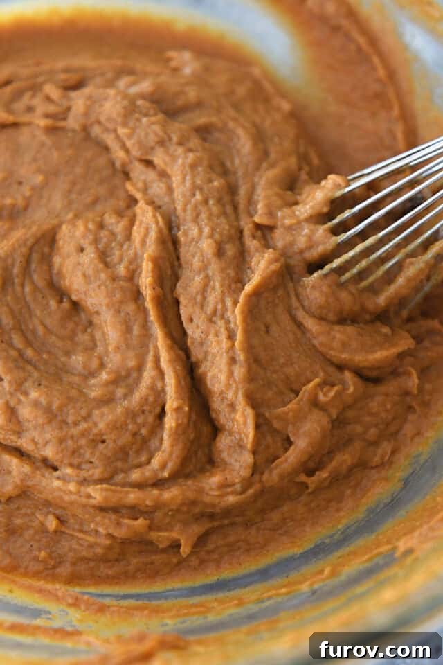 Whisking pumpkin muffin batter in glass bowl.