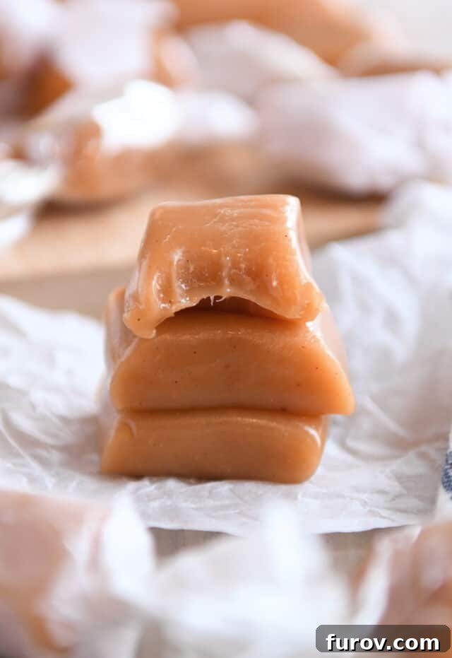 Three apple cider caramels stacked with the top caramel bitten in half.