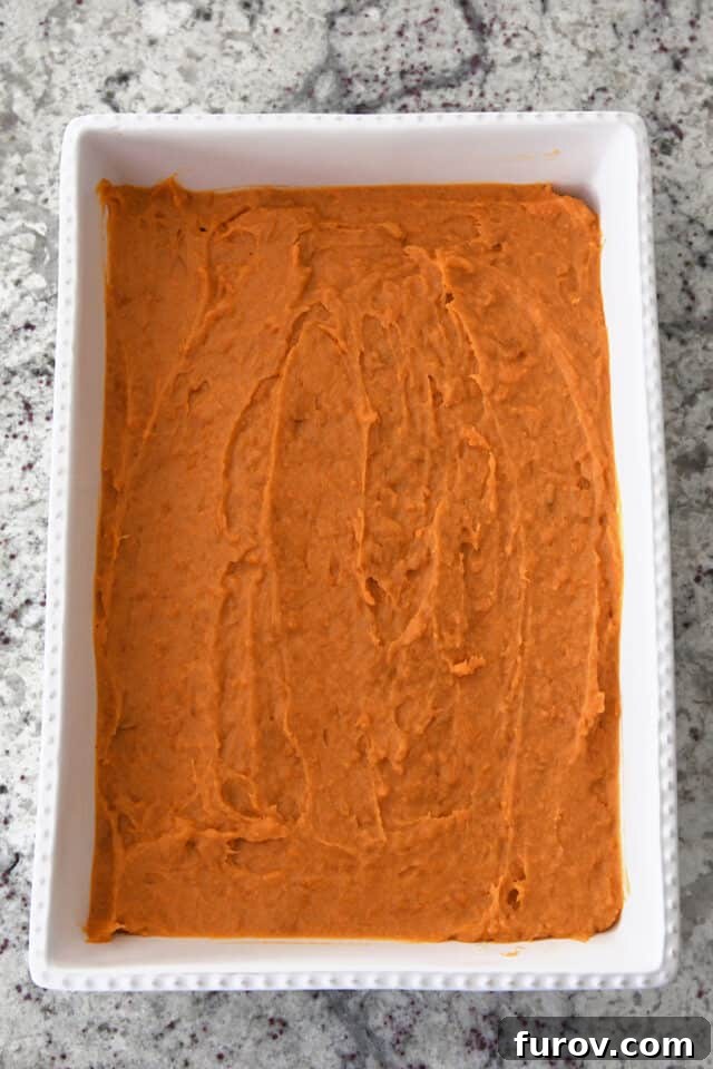 Sweet Potato Pecan Crumble Bake 5 A white baking dish with the creamy sweet potato filling spread smoothly and evenly, ready for the topping.