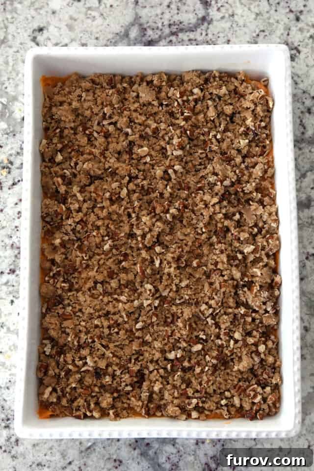 Sweet Potato Pecan Crumble Bake 6 A white baking dish showcasing the sweet potato filling generously covered with the buttery pecan topping, ready to be baked.