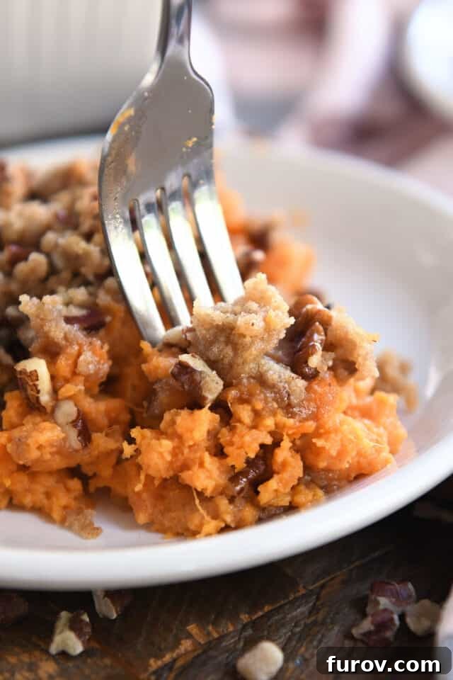 Sweet Potato Pecan Crumble Bake 8 A fork scooping a perfect bite of sweet potato casserole, revealing the smooth filling and crunchy pecan topping.