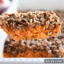 Serving spoon with sweet potato casserole and pecan topping.