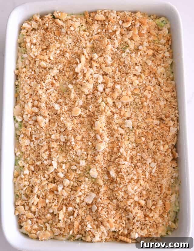 Buttery Ritz cracker topping spread evenly over the cheesy broccoli chicken and rice casserole in a white 9x13-inch baking pan, ready for baking.