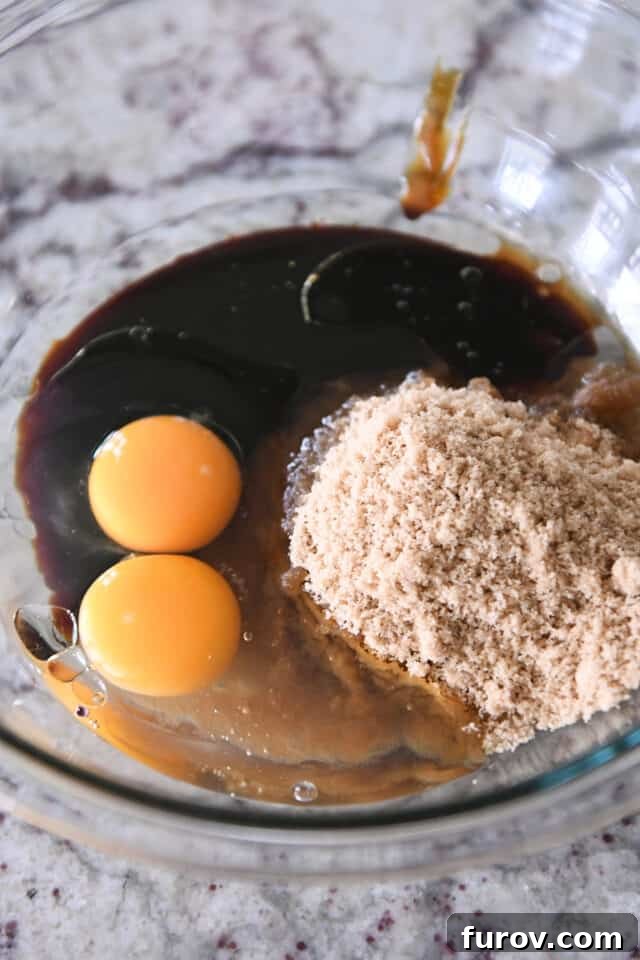 Glass bowl with wet ingredients: eggs, brown sugar, molasses and oil, ready for mixing.