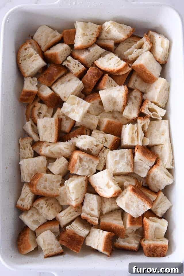 Cinnamon Streusel French Toast Casserole 3 White pan with bread cubes.