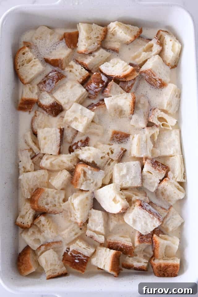 Cinnamon Streusel French Toast Casserole 4 White pan with bread and egg and milk mixture.