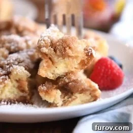 Cinnamon Streusel French Toast Casserole 10 Fork skewering two bites of baked French toast on white plate.