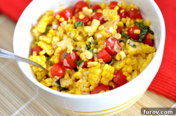 Close-up of a white bowl filled with a delightful summer corn, tomato, and basil salad.