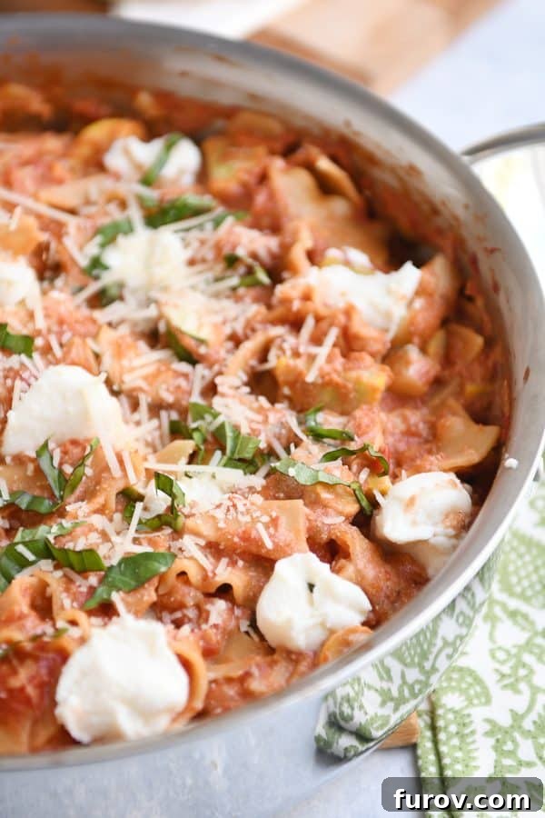 Vibrant Skillet Vegetable Lasagna in a stainless steel skillet, garnished with creamy ricotta cheese dots.