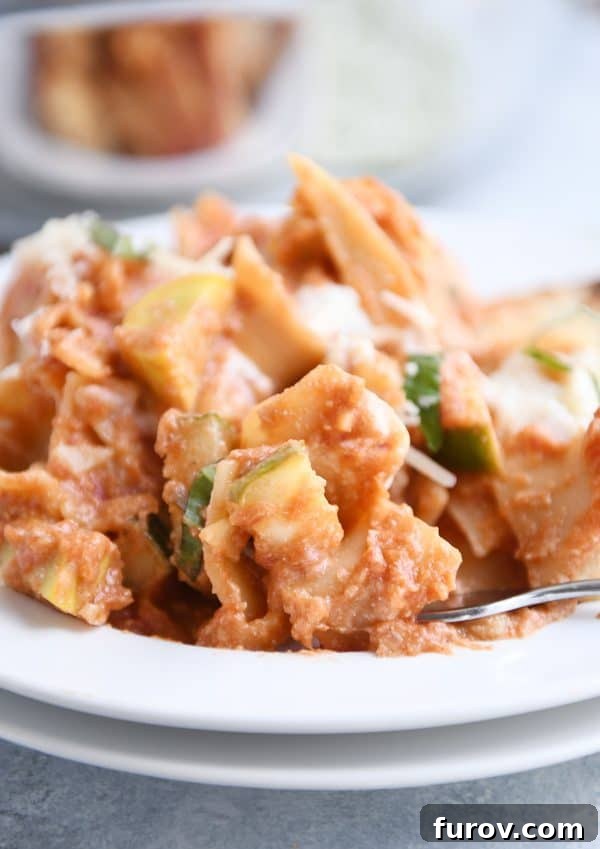 A serving of Skillet Vegetable Lasagna scooped onto a white plate, showcasing layers of pasta, vegetables, and cheese.