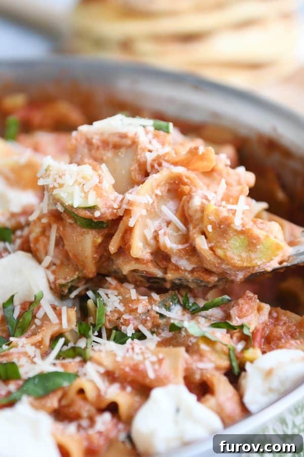 A serving spoon lifting a generous portion of creamy Skillet Vegetable Lasagna from the pan, highlighting the cheesy, saucy texture.