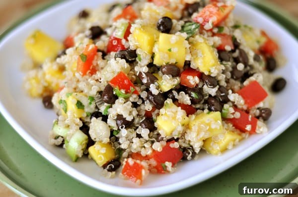Close-up of a white plate holding a serving of Mango and Black Bean Quinoa Salad, highlighting the fresh ingredients.