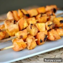 Close-up of golden grilled sweet potato skewers on a white serving platter.