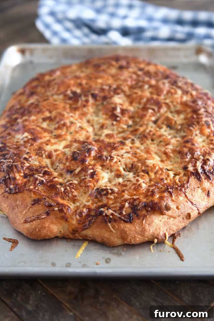 Freshly baked Italian cheese bread, golden brown with bubbling melted cheese, still on the half sheet pan.