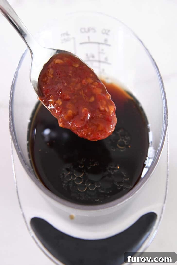 Close-up shot of a small bowl containing the rich, dark blend of soy sauce, rice vinegar, chili garlic sauce, brown sugar, and sesame oil, ready to be whisked.