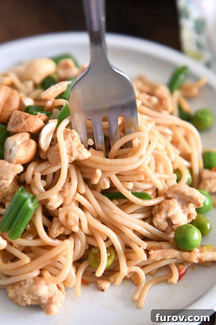 A fork twirling a perfect bite of spicy garlic ramen noodles, adorned with peas and green onions, capturing the enticing texture and vibrant colors.