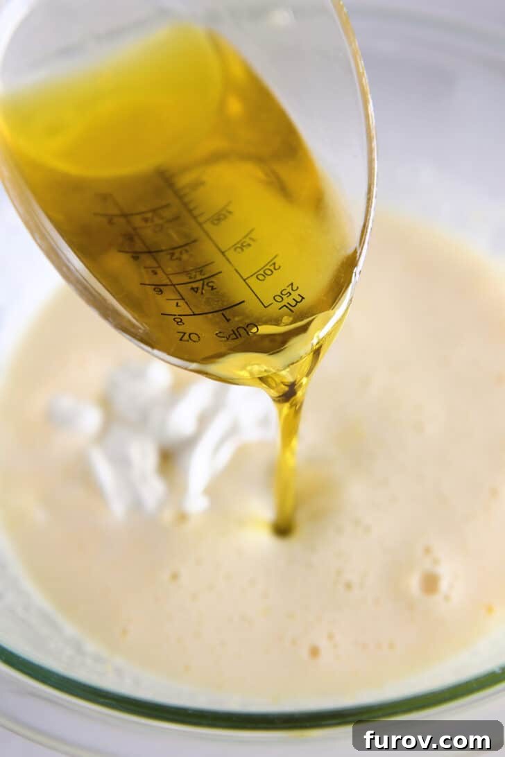 Pouring olive oil into bowl with cake batter ingredients.