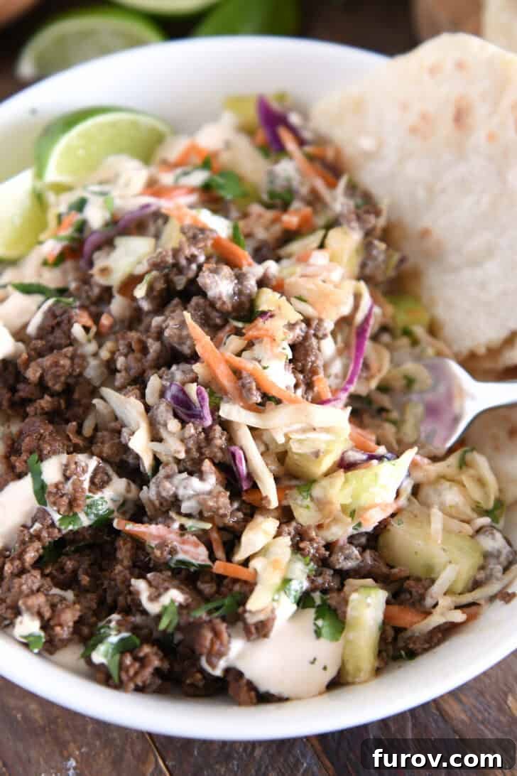 White bowl with all components tossed together: rice, slaw, sauce, and Korean beef, showing a well-mixed and appetizing meal.
